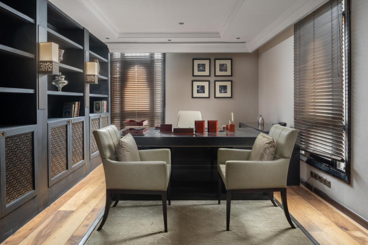 Sofitel Shahd Al Madinah Hotel Medina Buitenkant foto The photo depicts a modern office space. It features a large, dark wooden desk at the center, with two matching chairs positioned in front of it. Behind the desk is a minimalist white chair. The walls are adorned with framed pictures and there are bu